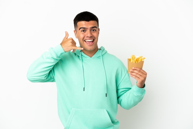 Young handsome man holding fried chips over isolated white background making phone gesture. Call me back sign