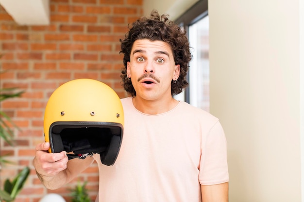 Young handsome man holding a motorbike helmet at home interior