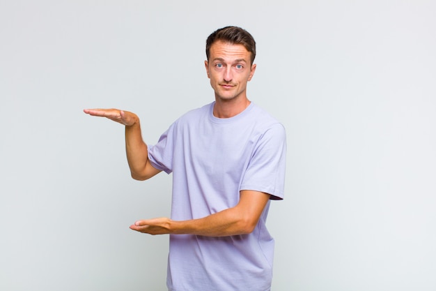 Young handsome man holding an object with both hands on side