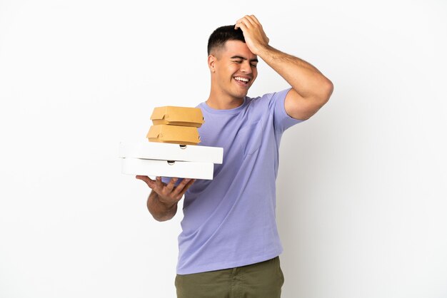 Photo young handsome man holding pizzas and burgers over isolated white background has realized something and intending the solution