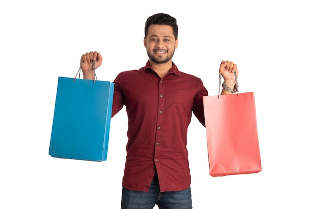 Young handsome man holding and posing with shopping bags on a white background