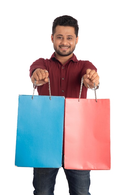 Young handsome man holding and posing with shopping bags on a white background