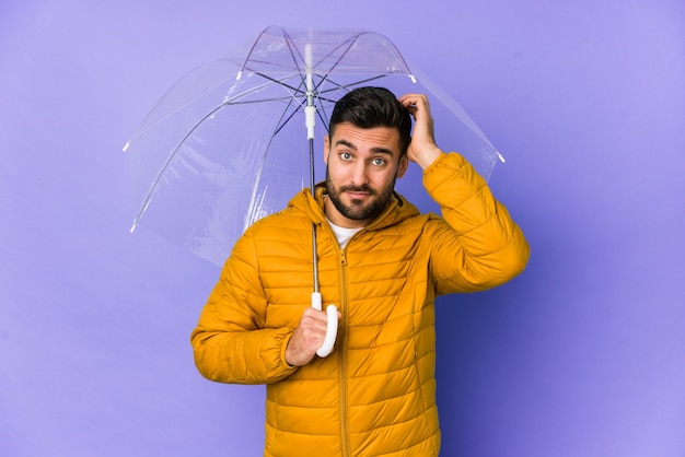 Young handsome man holding an umbrella isolated being shocked, she has remembered important meeting.