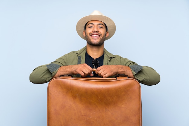 Young handsome man holding a vintage briefcase over isolated blue background