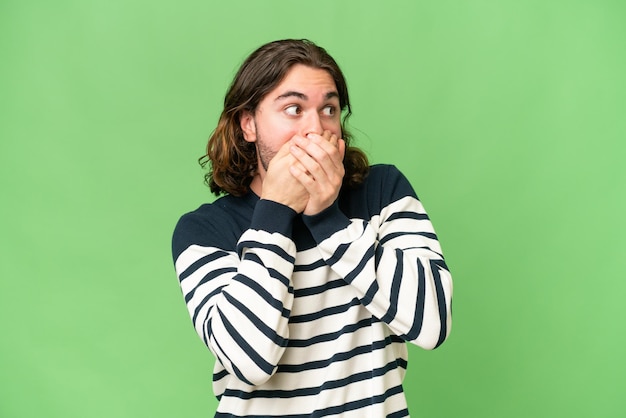 Photo young handsome man over isolated background covering mouth and looking to the side