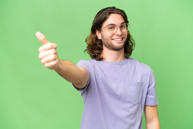 Foto giovane uomo bello su sfondo isolato dando un pollice in alto gesto