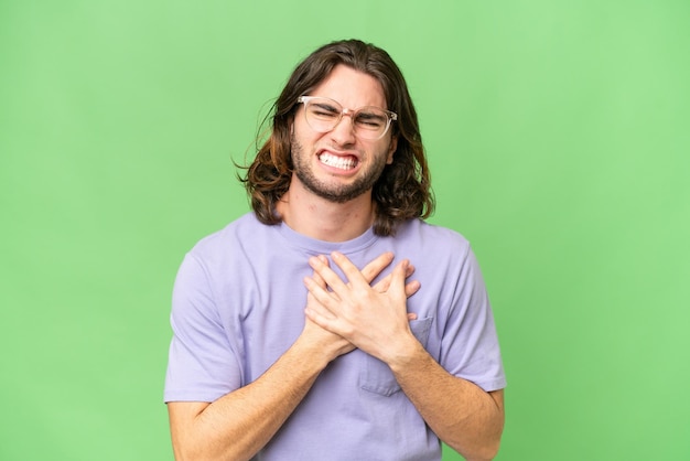 Young handsome man over isolated background having a pain in the heart