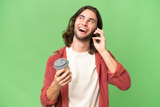 奪うコーヒーと携帯電話を保持している孤立した背景の上の若いハンサムな男