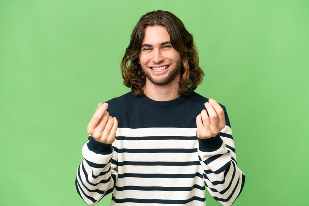 Young handsome man over isolated background making money gesture