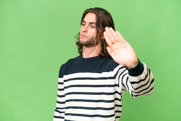 Young handsome man over isolated background making stop gesture and disappointed