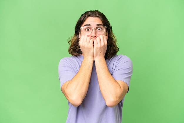 Young handsome man over isolated background nervous and scared putting hands to mouth