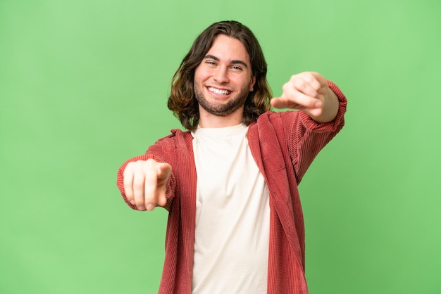 Young handsome man over isolated background points finger at you while smiling