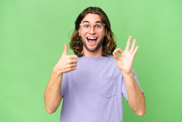 Young handsome man over isolated background showing ok sign and thumb up gesture