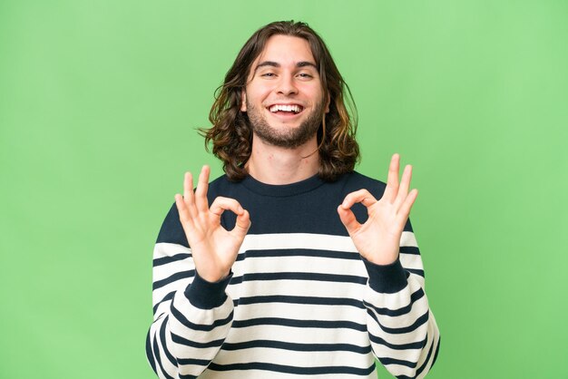 Young handsome man over isolated background showing ok sign with two hands