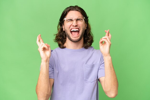 Young handsome man over isolated background with fingers crossing