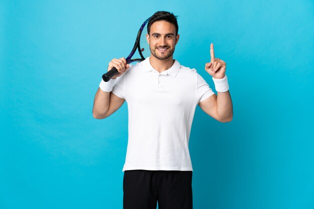 Young handsome man isolated  playing tennis and pointing up