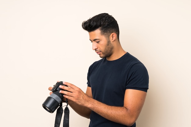 Young handsome man over isolated wall with a professional camera