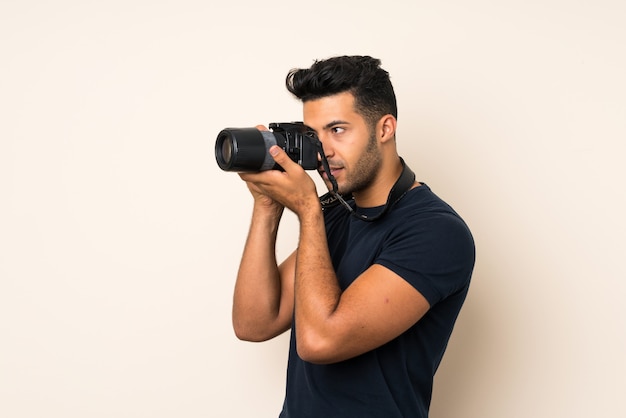 Young handsome man over isolated wall with a professional camera