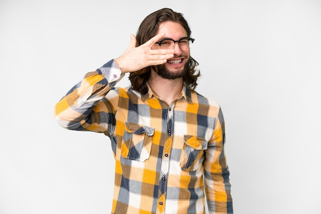 Young handsome man over isolated white background covering eyes by hands and smiling