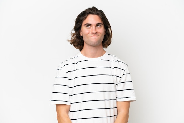 Young handsome man isolated on white background having doubts while looking up