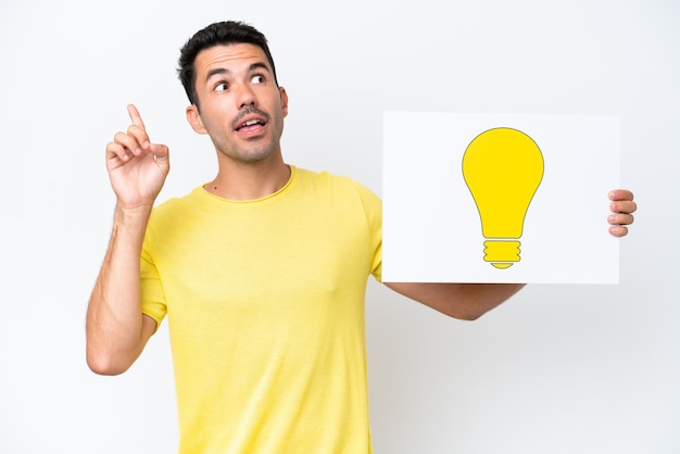 Young handsome man over isolated white background holding a placard with bulb icon and thinking