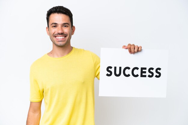 Young handsome man over isolated white background holding a placard with text SUCCESS with happy expression