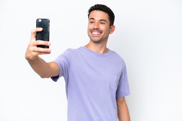 携帯電話で selfie を作る分離の白い背景の上の若いハンサムな男