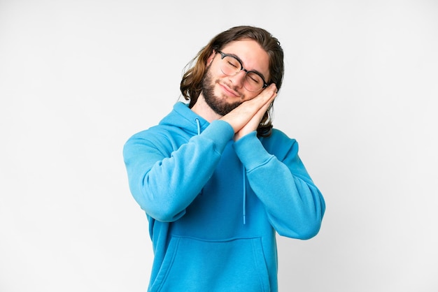 Giovane uomo bello su sfondo bianco isolato che fa il gesto del sonno in un'espressione adorabile