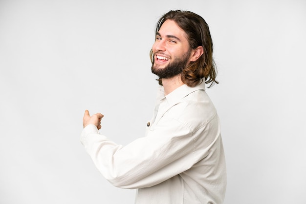 Young handsome man over isolated white background pointing back