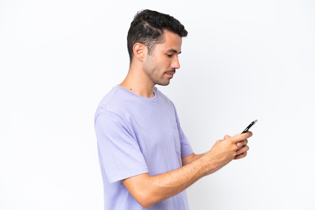 携帯電話でメッセージまたは電子メールを送信する孤立した白い背景の上の若いハンサムな男