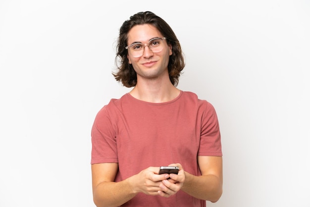 Young handsome man isolated on white background sending a message with the mobile