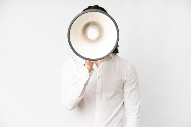 Photo young handsome man over isolated white background shouting through a megaphone to announce something