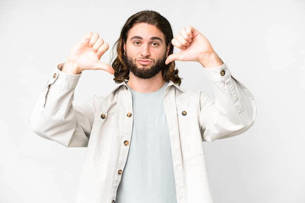 Young handsome man over isolated white background showing thumb down with two hands