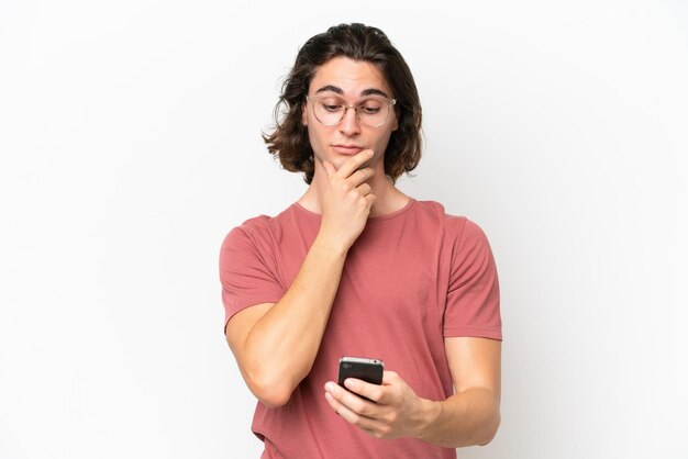 Foto giovane uomo bello isolato su sfondo bianco pensando e inviando un messaggio