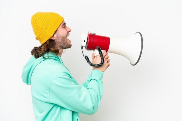 Young handsome man isolated on white chroma background shouting through a megaphone