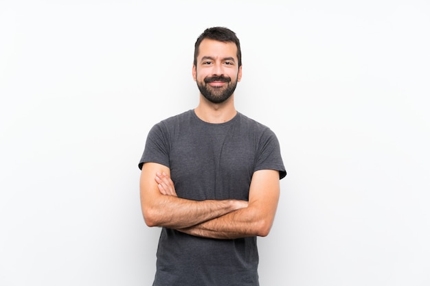 Young handsome man over isolated white wall keeping the arms crossed in frontal position