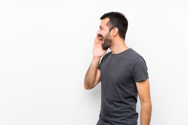 Young handsome man over isolated white wall shouting with mouth wide open to the lateral