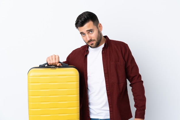 Молодой красавец над белой стене в отпуск с чемоданом путешествия и несчастной