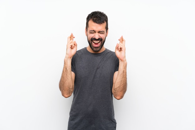 Young handsome man over isolated white wall with fingers crossing