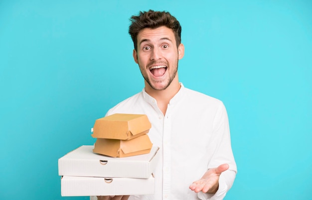 Young handsome man isolated with fast food mock up boxes delivery and take away concept