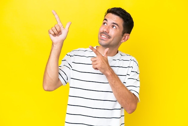 Young handsome man over isolated yellow background pointing with the index finger a great idea