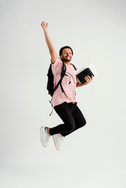 young handsome man jumping with backpack
