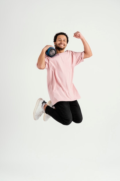 young handsome man jumping with speaker