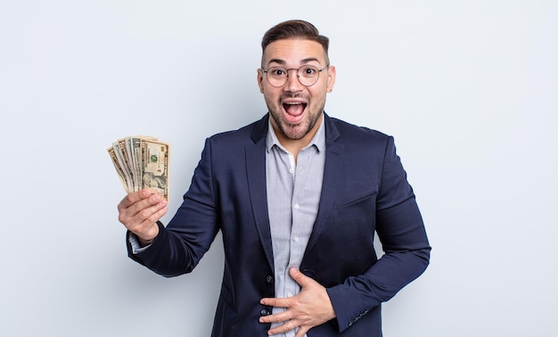 Young handsome man laughing out loud at some hilarious joke dollar banknotes concept