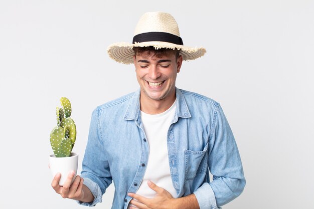 Young handsome man laughing out loud at some hilarious joke. farmer holding a decorative cactus