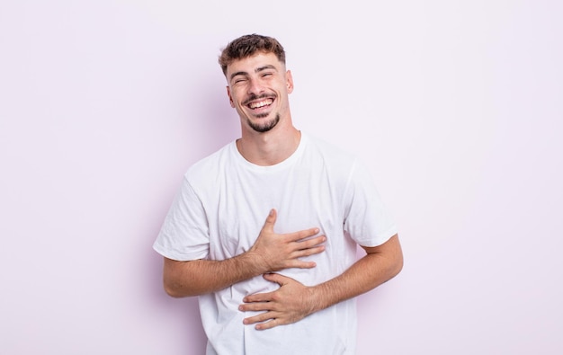 Young handsome man laughing out loud at some hilarious joke, feeling happy and cheerful, having fun