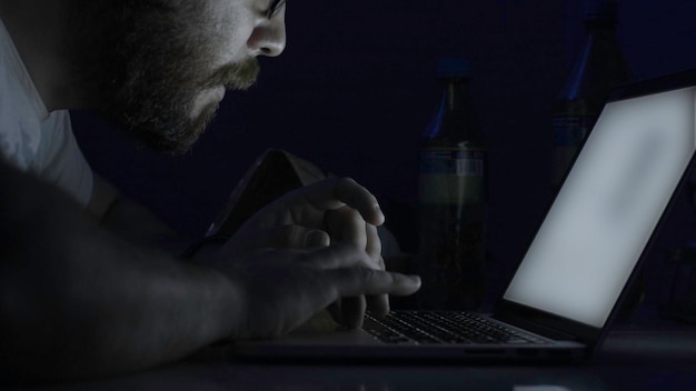젊은 잘생긴 남자는 밤에 컴퓨터에서 배우고 밤에 노트북을 사용하는 남자는 방에서