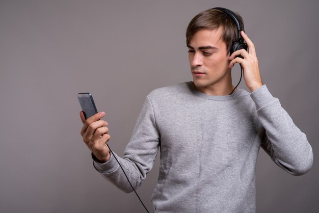 Young handsome man listening to music and ready for gym against