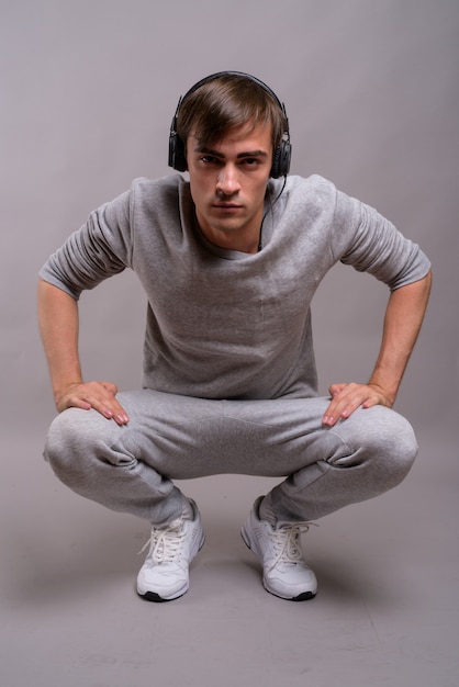 Young handsome man listening to music and ready for gym against