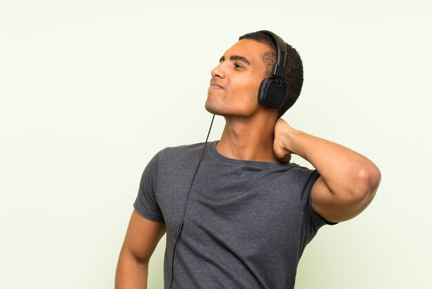 Photo young handsome man listening music with a mobile over isolated green wall